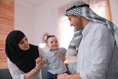 Photo of Happy Muslim family with little son in living room