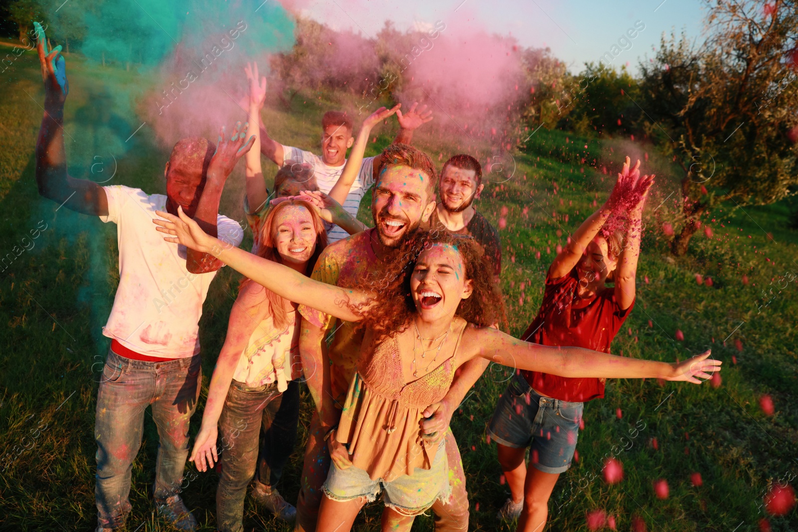 Photo of Happy friends with colorful powder dyes outdoors. Holi festival celebration