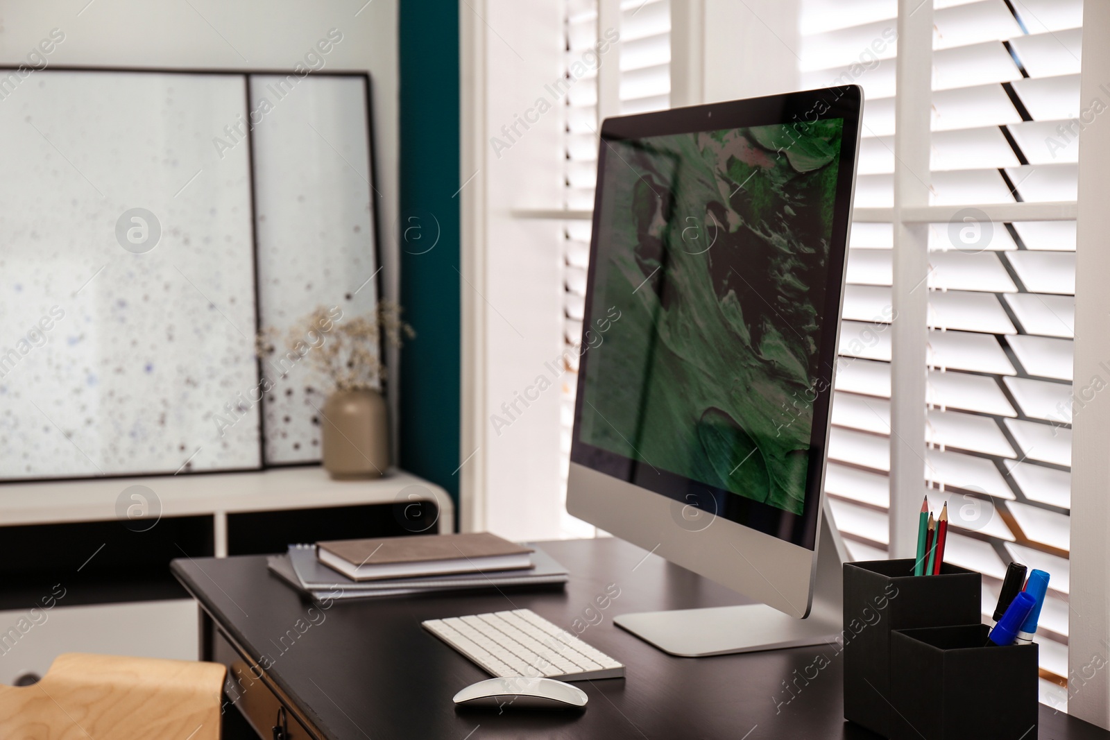 Photo of Comfortable workplace near window with white horizontal blinds in room