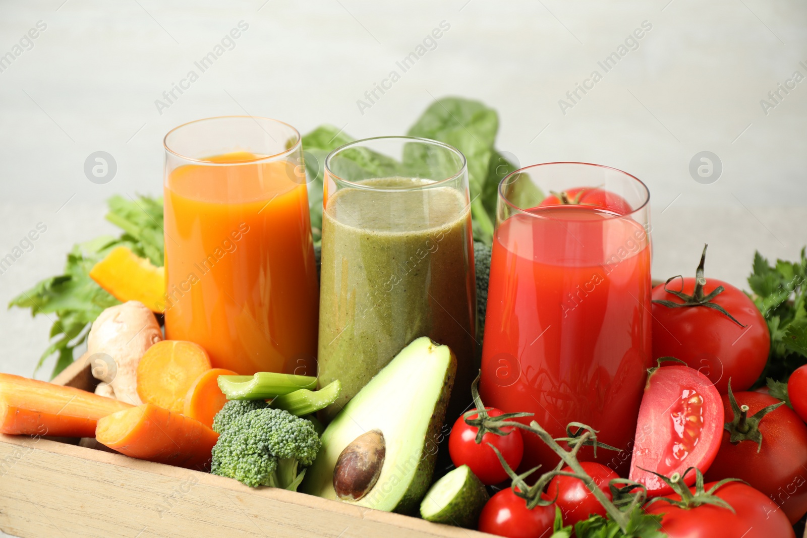 Photo of Delicious vegetable juices and fresh ingredients on light background