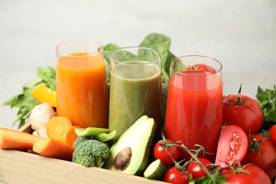 Photo of Delicious vegetable juices and fresh ingredients on light background