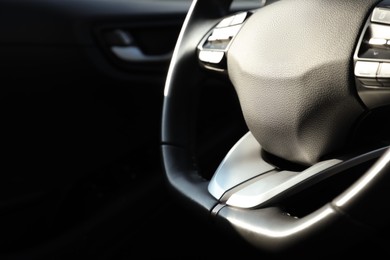 Photo of Black steering wheel inside of modern car, closeup. Space for text