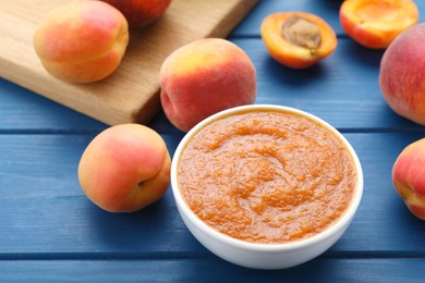 Photo of Apricot puree in bowl and fresh fruits on blue wooden table