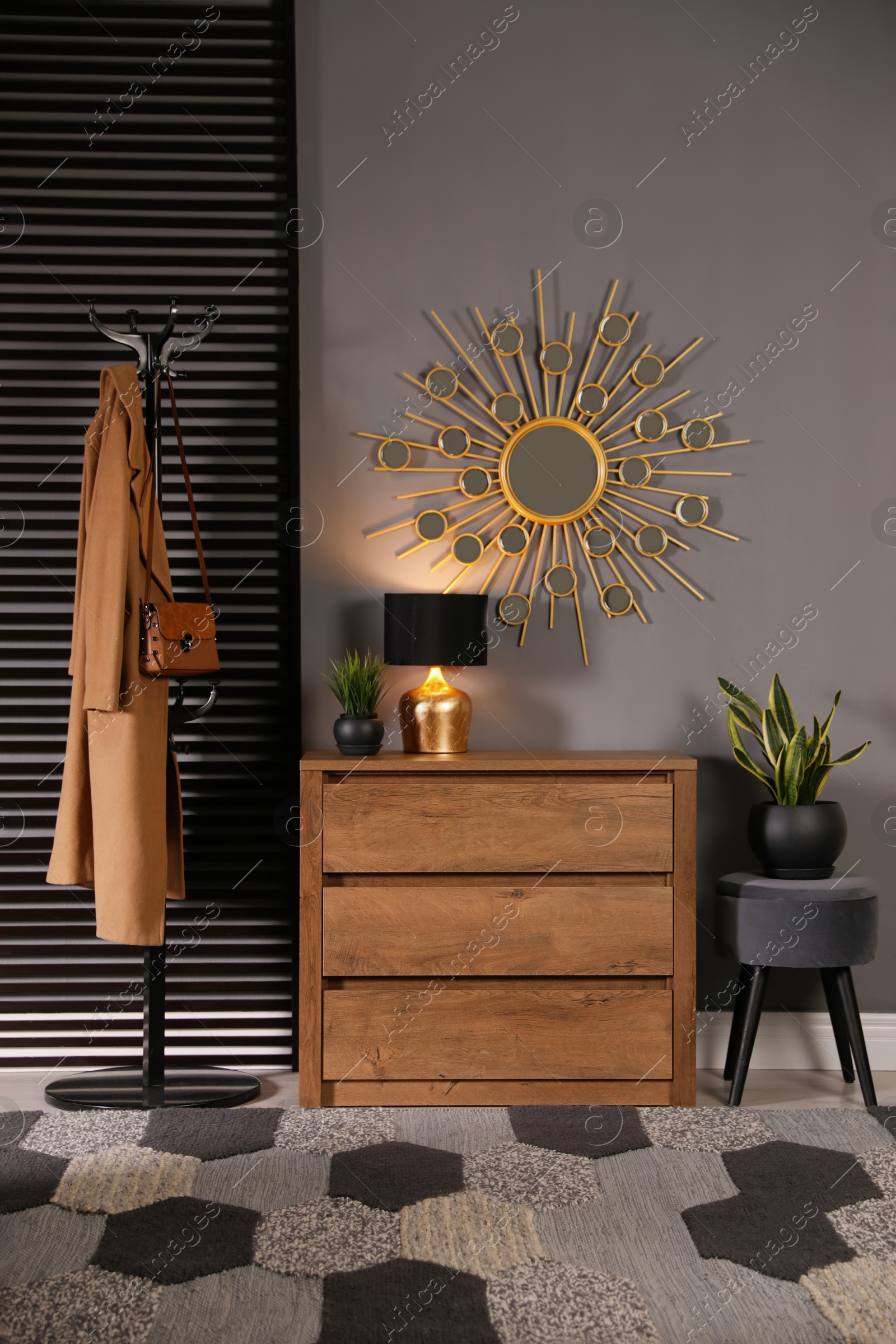 Photo of Wooden chest of drawers with decor, coat stand and mirror in hallway. Interior design