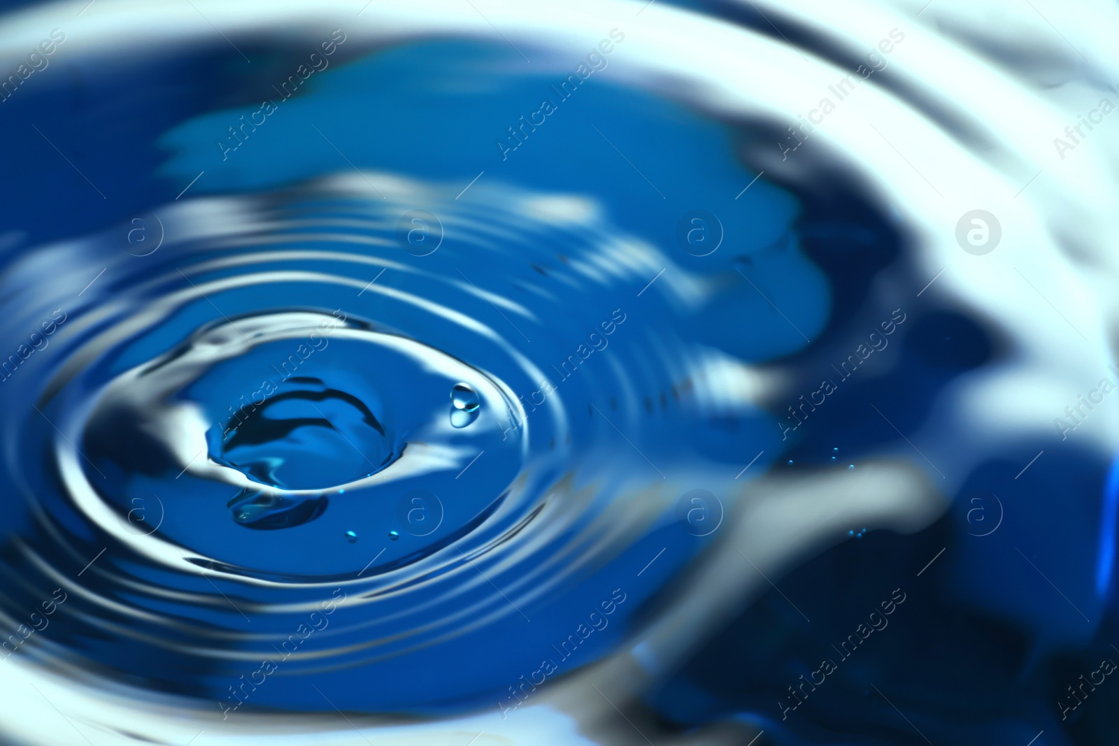 Photo of Splash of clear water on blue background, closeup