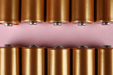 Photo of New AA batteries on pink background, flat lay