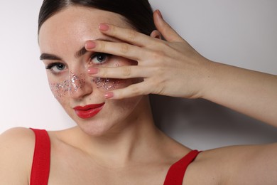 Photo of Beautiful woman with glitter freckles on light background, closeup