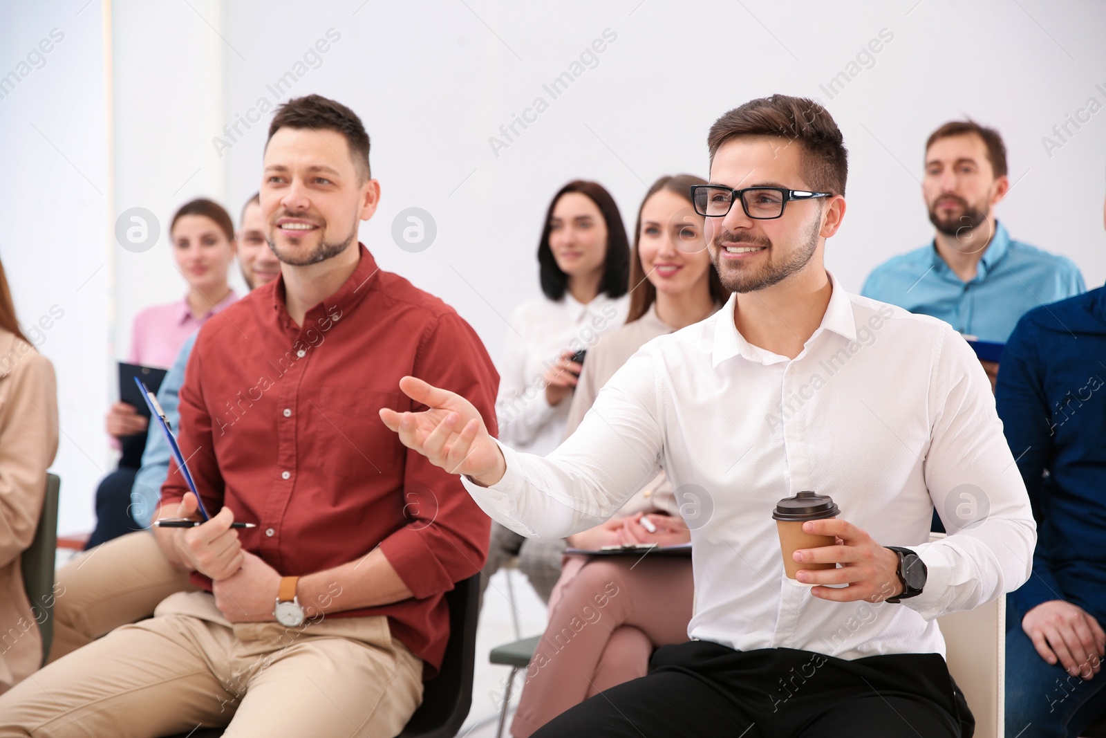 Photo of Young man asking question at business training indoors