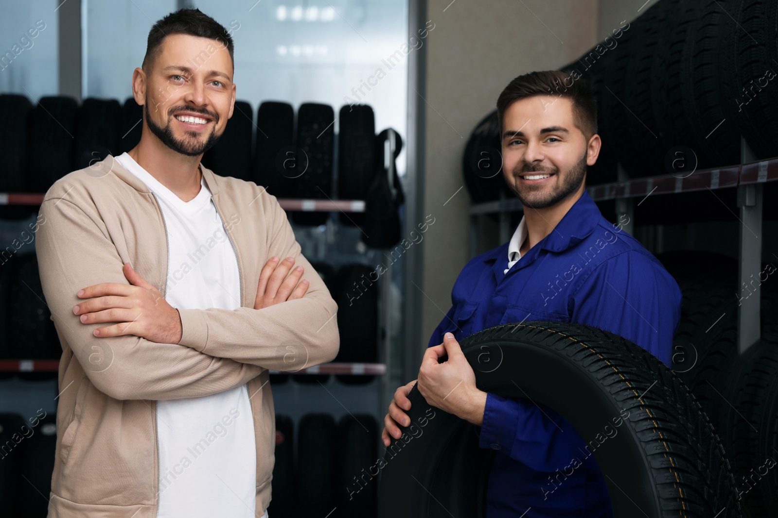 Photo of Mechanic helping client to choose car tire in auto store