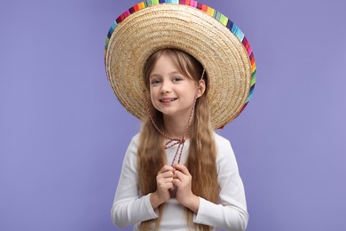 Cute girl in Mexican sombrero hat on purple background