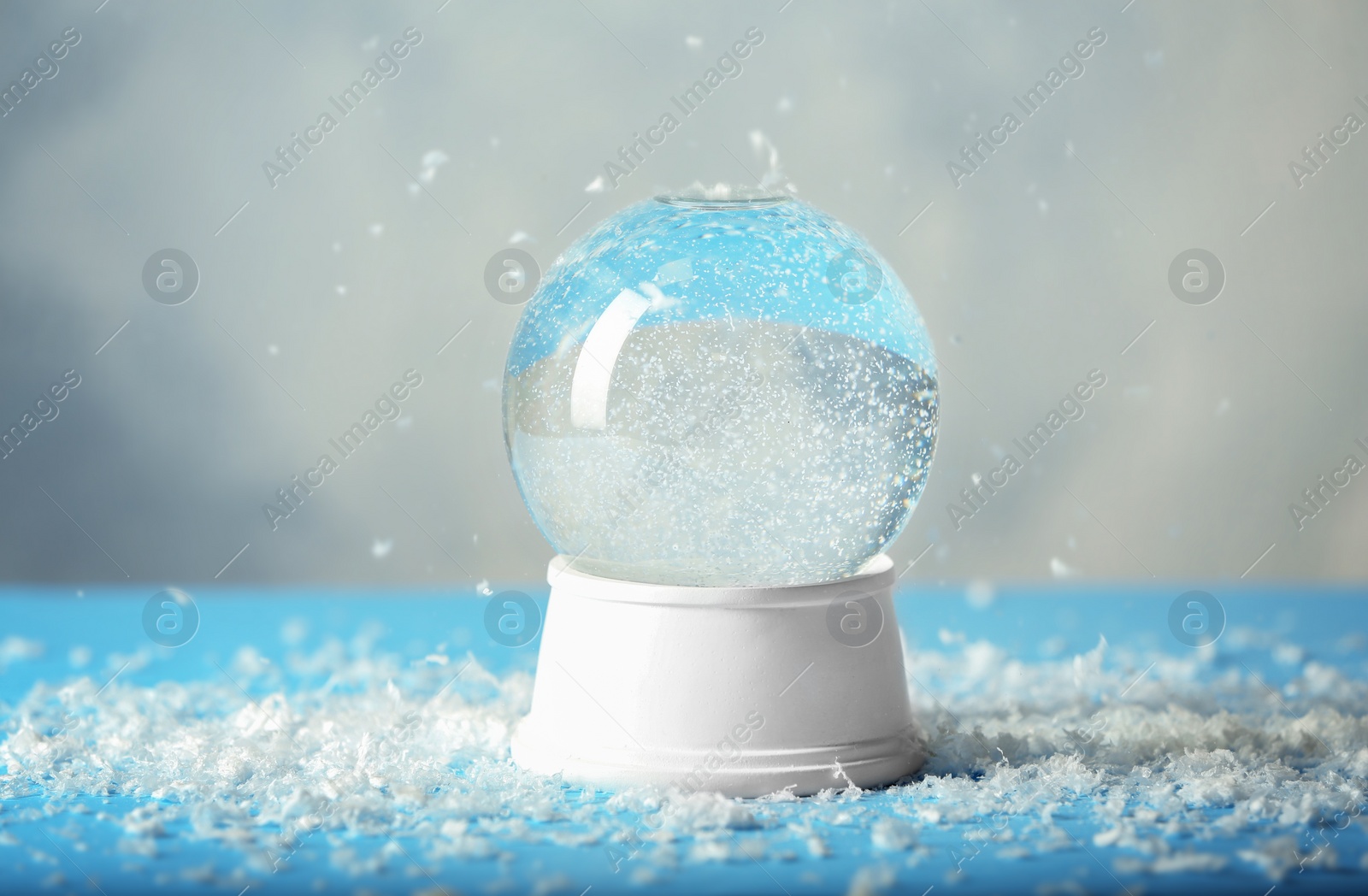Photo of Magical empty snow globe on table against light background