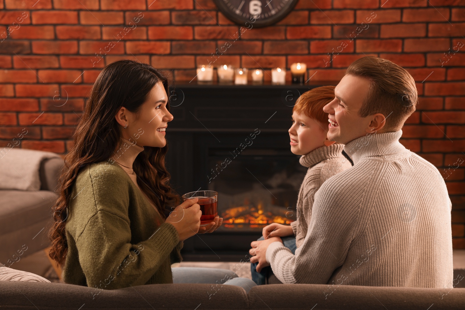 Photo of Happy family spending time together near fireplace at home
