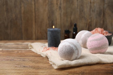 Photo of Bath bombs, sea salt, and burning candle on table, space for text