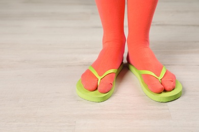 Photo of Woman wearing bright socks with flip-flops standing on floor. Space for design