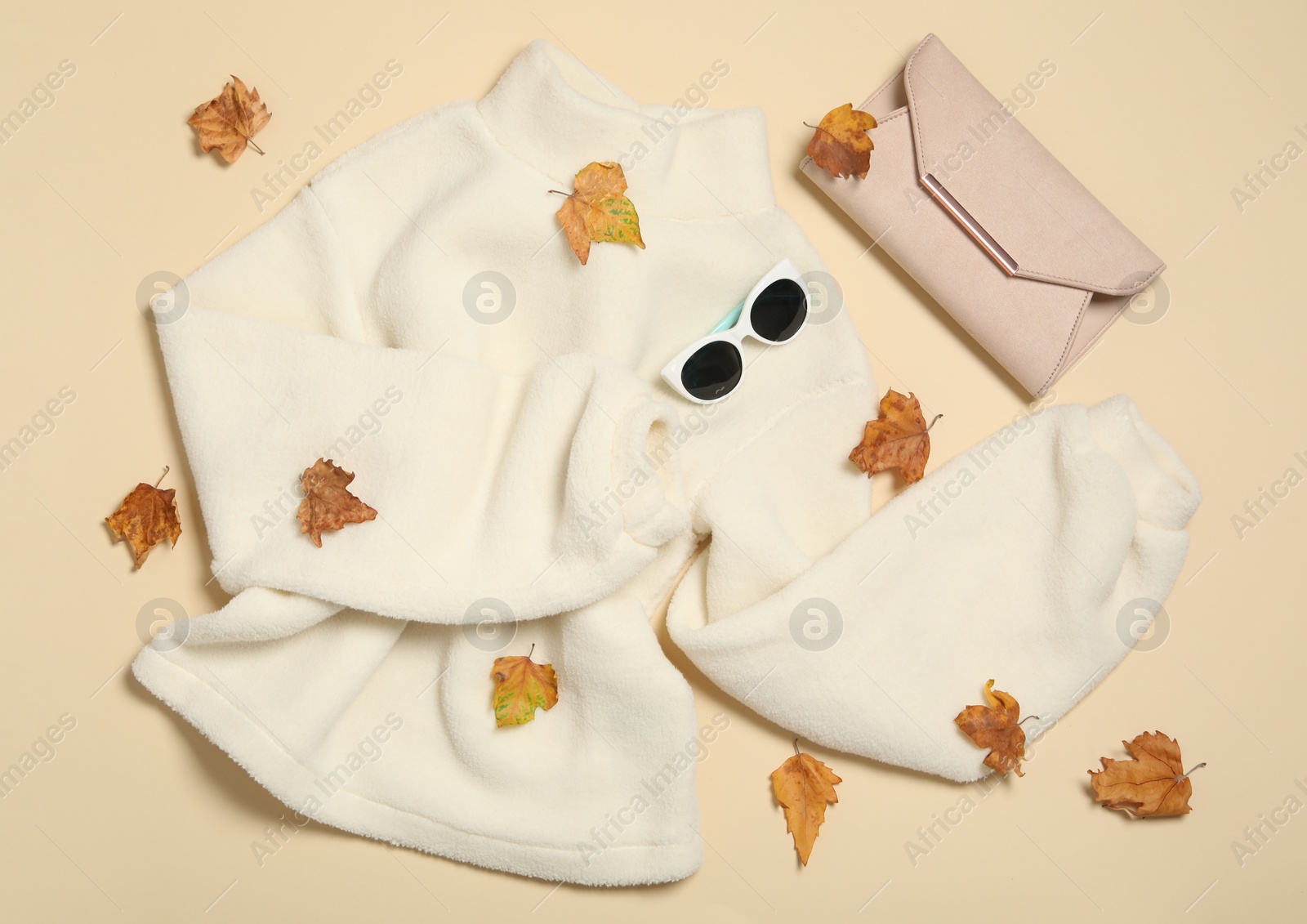 Photo of Flat lay composition with sweater and dry leaves on beige background. Autumn season