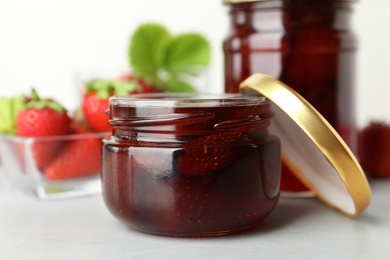 Photo of Delicious pickled strawberry jam and fresh berries on light table