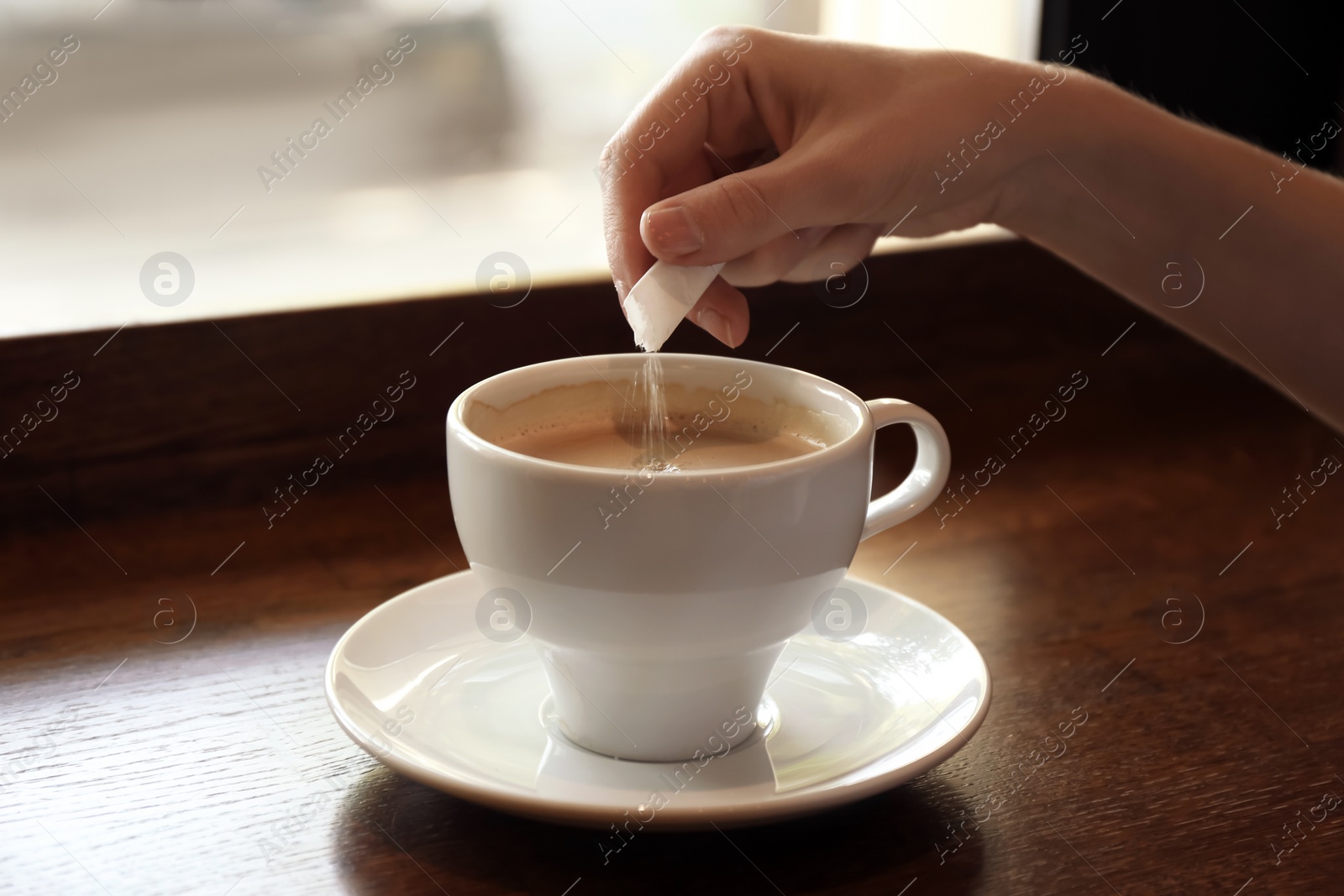 Photo of Woman adding sugar to fresh aromatic coffee on table, closeup