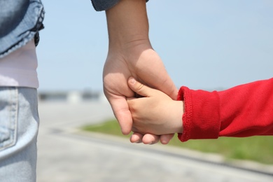 Little child holding hands with his father  outdoors, closeup. Family weekend