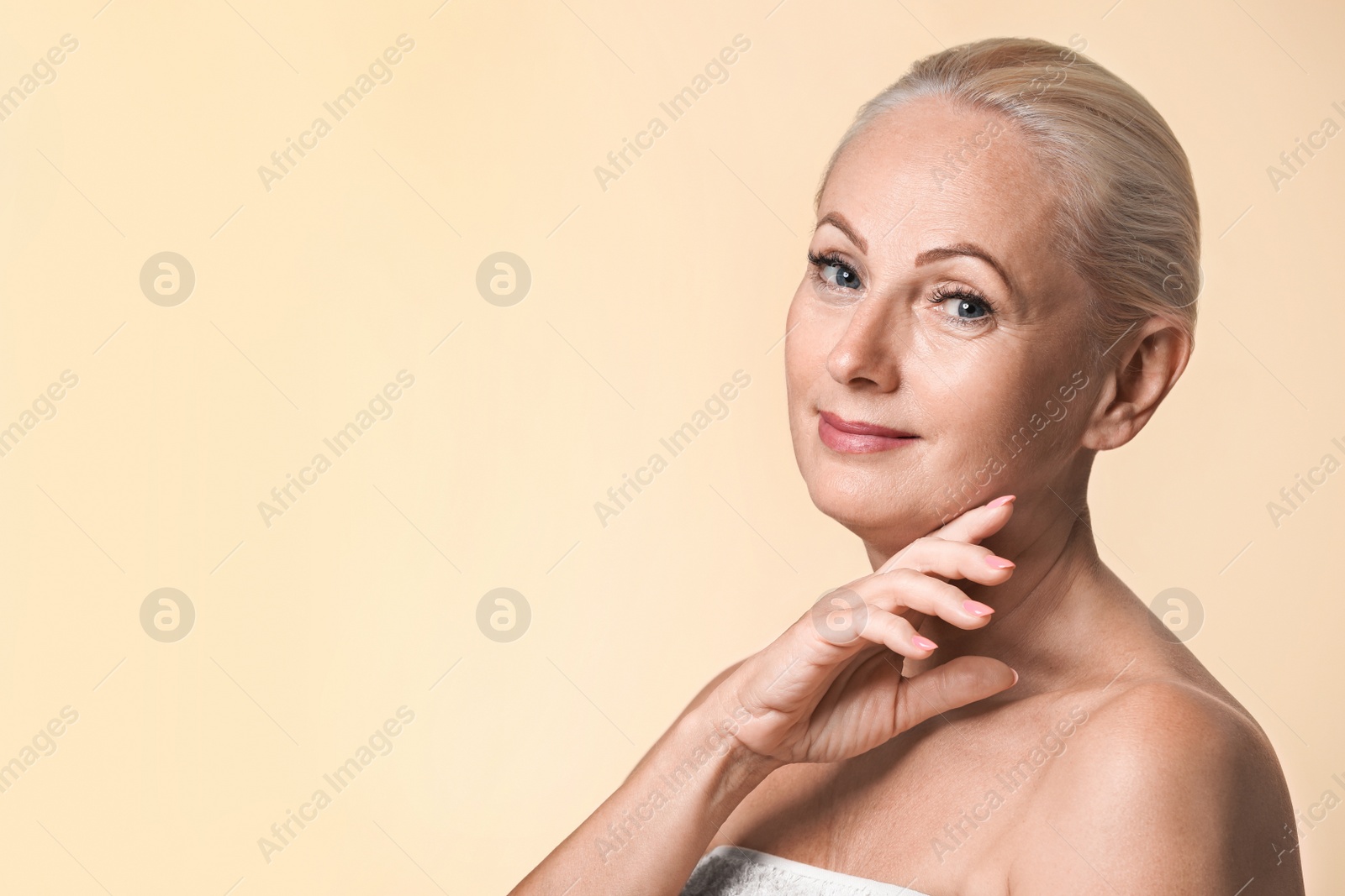 Photo of Portrait of beautiful mature woman with perfect skin on beige background. Space for text