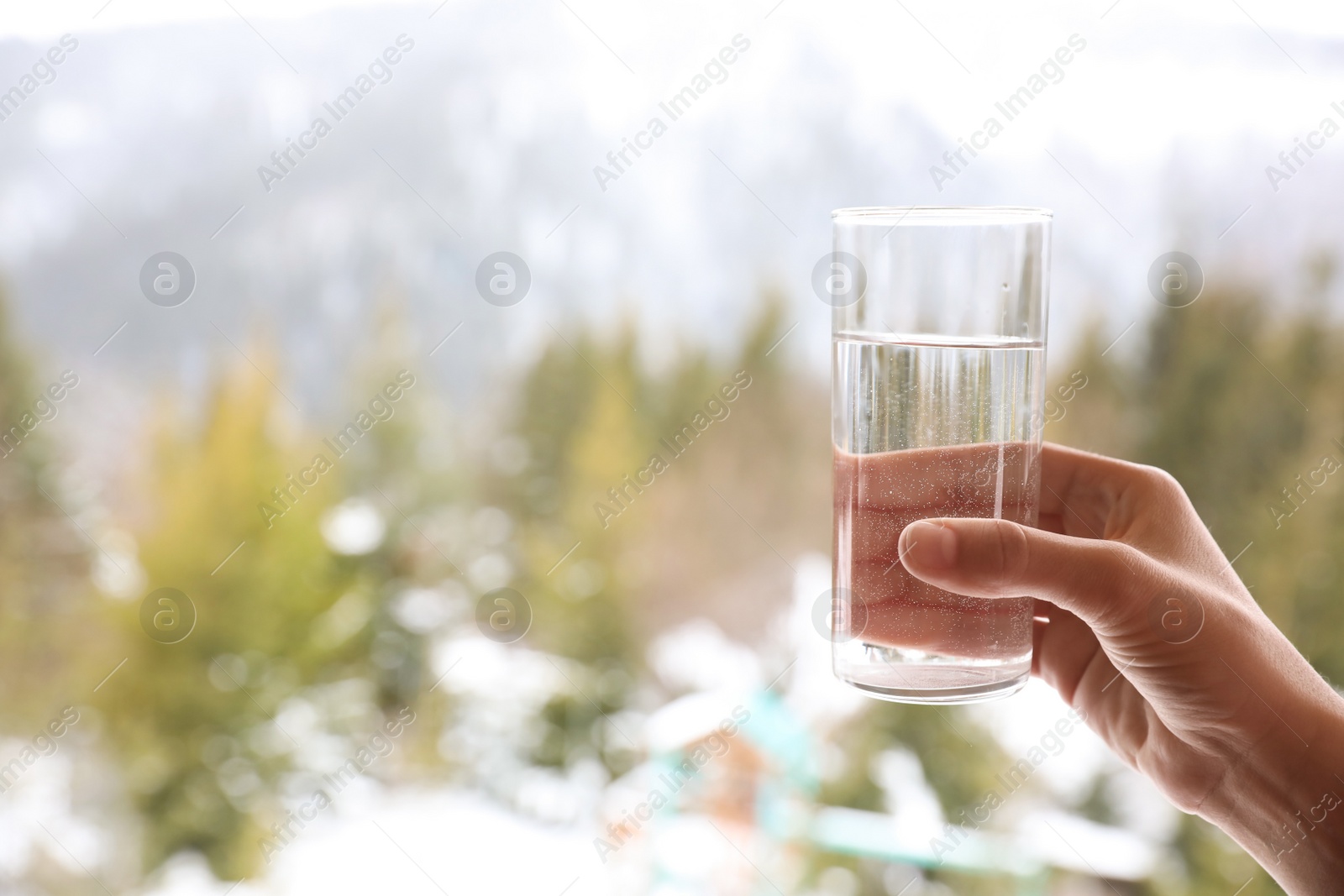 Photo of Woman holding glass of water outdoors on winter morning, closeup. Space for text