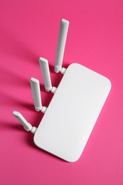 Photo of New white Wi-Fi router on pink background, top view