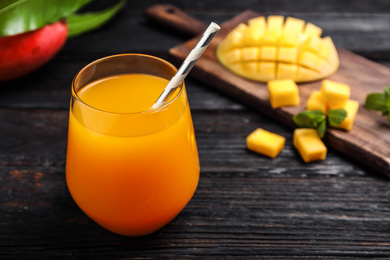 Photo of Fresh delicious mango drink on wooden table. Space for text