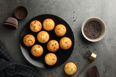 Delicious freshly baked muffins with chocolate chips on gray table, flat lay