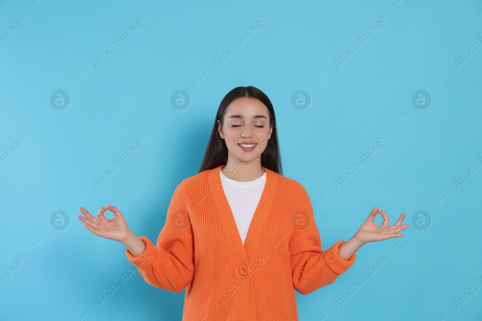 Photo of Find zen. Beautiful young woman meditating on light blue background