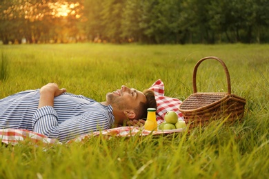 Photo of Young man lying on picnic blanket in park