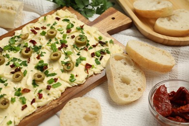 Photo of Fresh natural butter board with cut olives, sun-dried tomatoes and bread on table