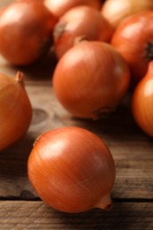 Photo of Many ripe onions on wooden table, closeup