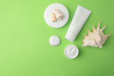 Different cosmetic products and seashells on light green background, flat lay. Space for text