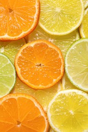 Photo of Slices of different citrus fruits as background, top view