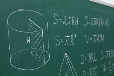 Different math formulas written with chalk on green board