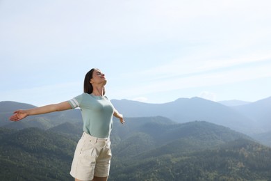 Photo of Beautiful young woman in peaceful mountains on sunny day. Feeling freedom