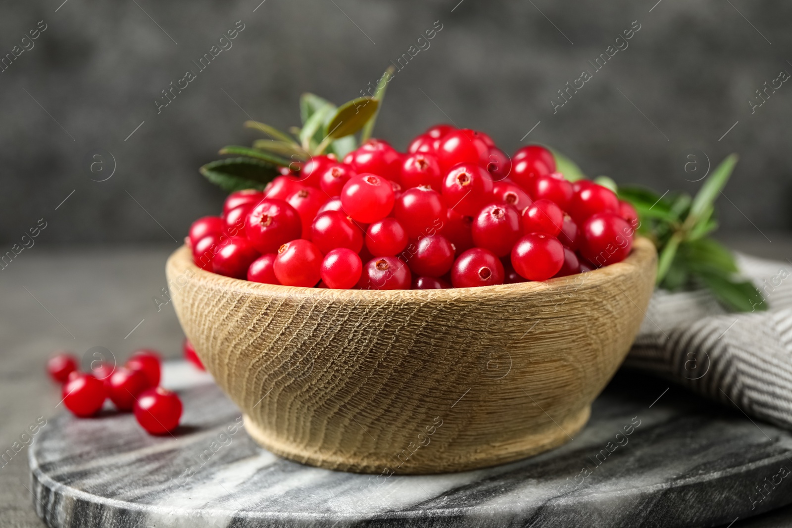 Photo of Tasty ripe cranberries on grey marble board, closeup