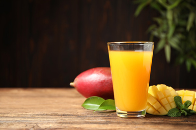 Fresh delicious mango drink on wooden table. Space for text