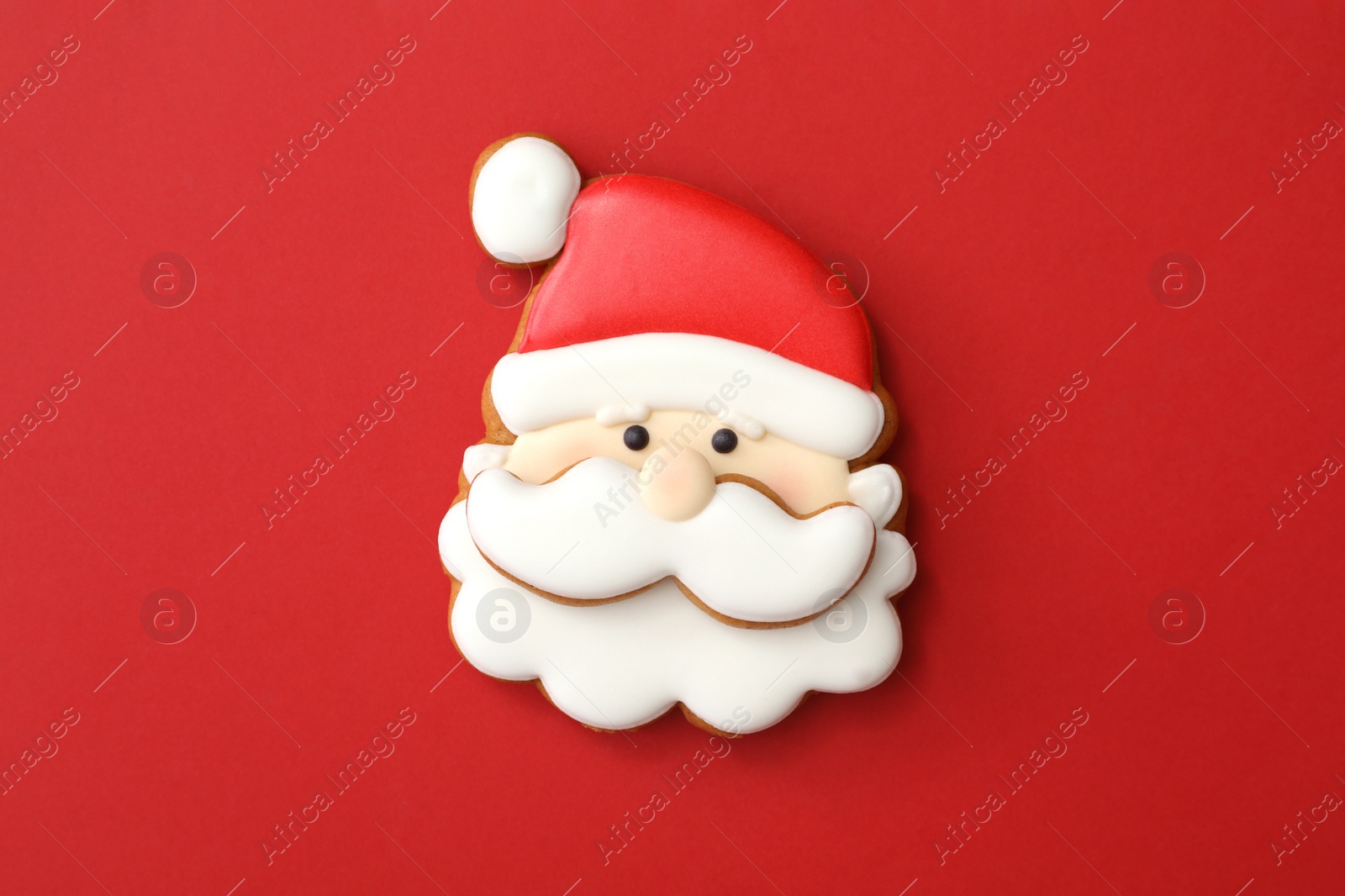 Photo of Christmas Santa Claus shaped gingerbread cookie on red background, top view