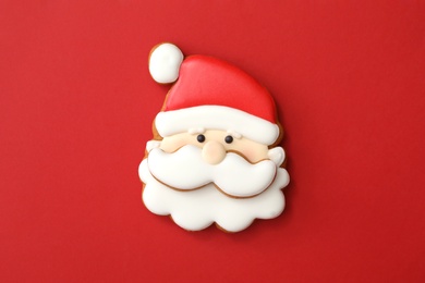 Photo of Christmas Santa Claus shaped gingerbread cookie on red background, top view