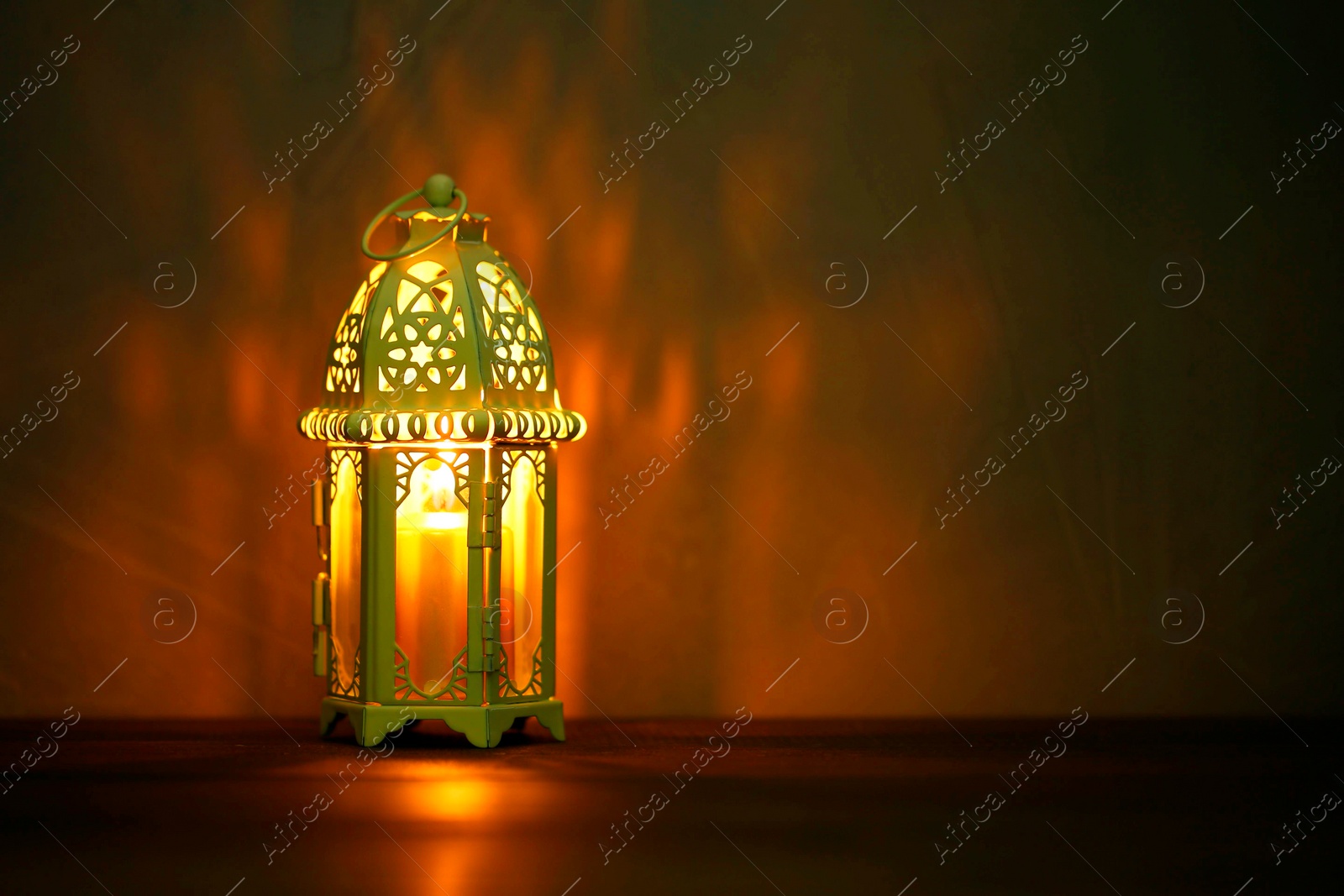 Photo of Decorative Arabic lantern on table against dark background. Space for text