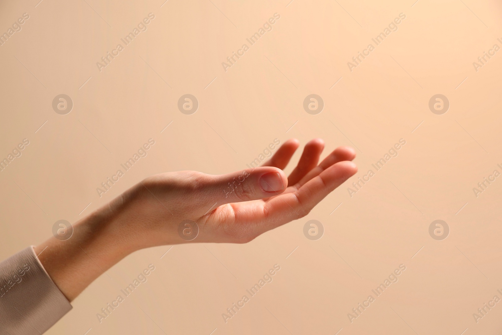 Photo of Woman holding something in hand on beige background, closeup