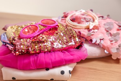 Photo of Stylish carnival costume with sequins, sunglasses and headbands on wooden table, closeup