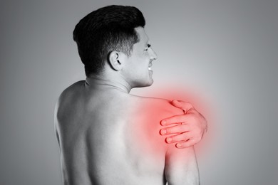 Man suffering from shoulder pain, back view. Black and white photo 
