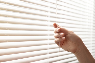 Photo of Woman opening window blinds, closeup. Space for text