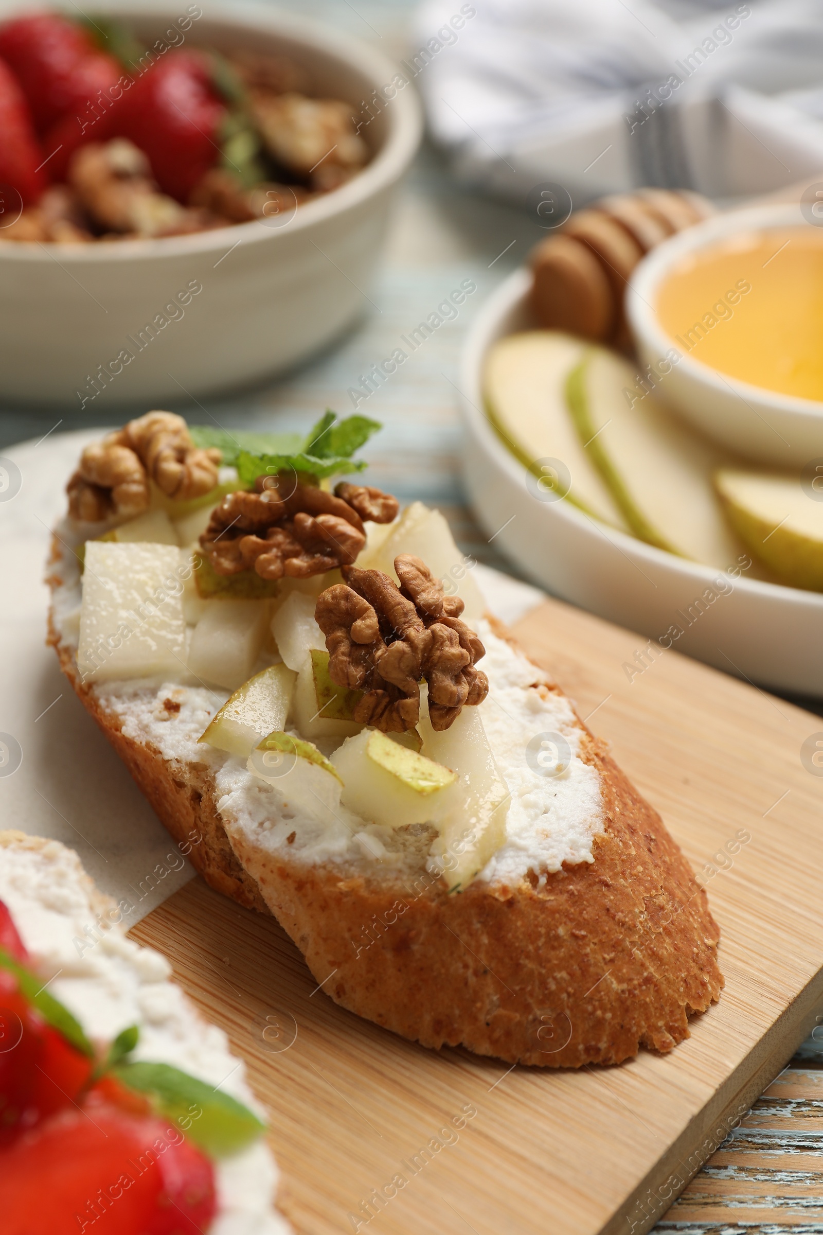 Photo of Delicious ricotta bruschetta with pear and walnut on wooden table, closeup