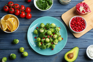 Photo of Tasty salad with Brussels sprouts and ingredients on blue wooden table, flat lay