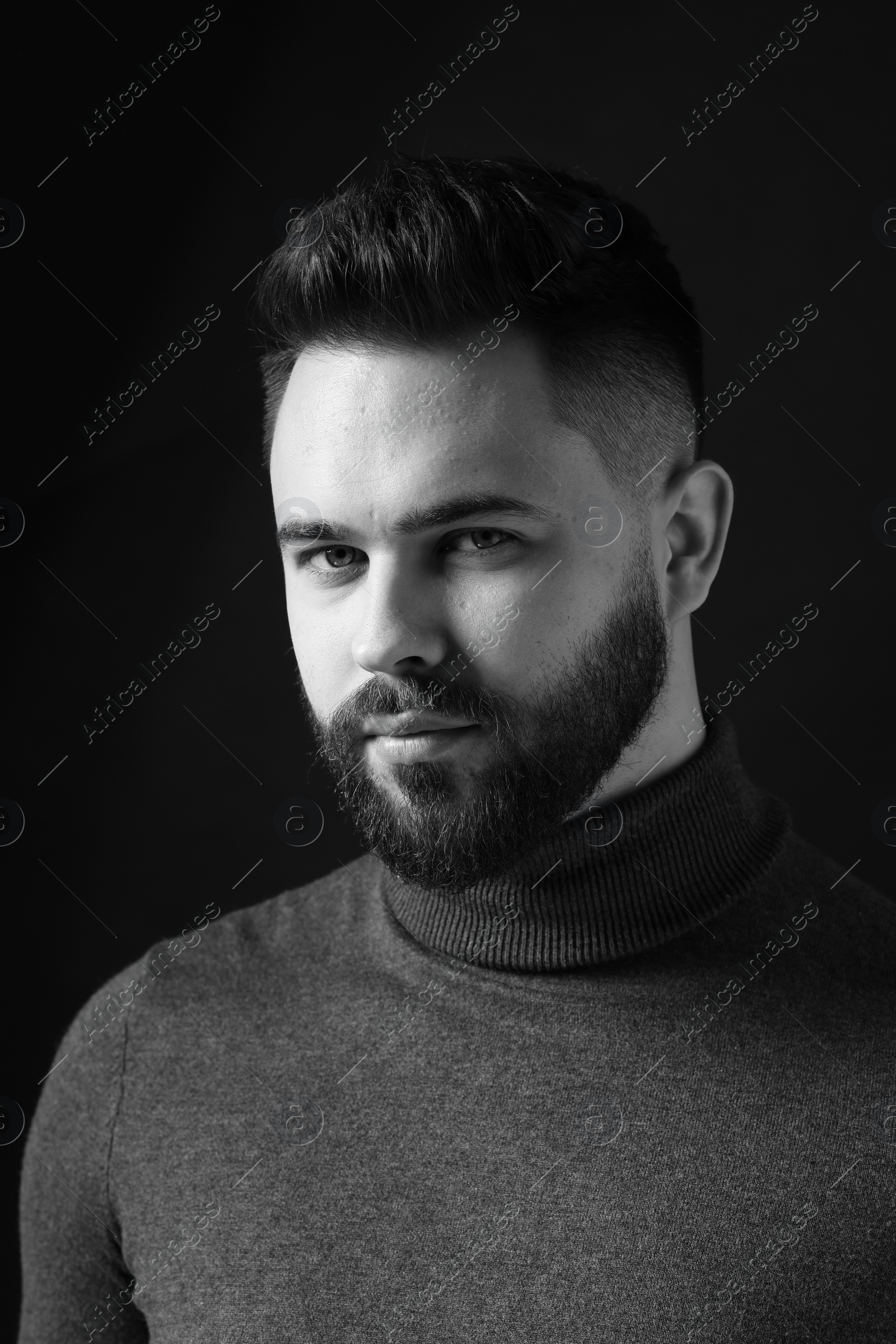 Photo of Portrait of handsome bearded man on dark background. Black and white effect