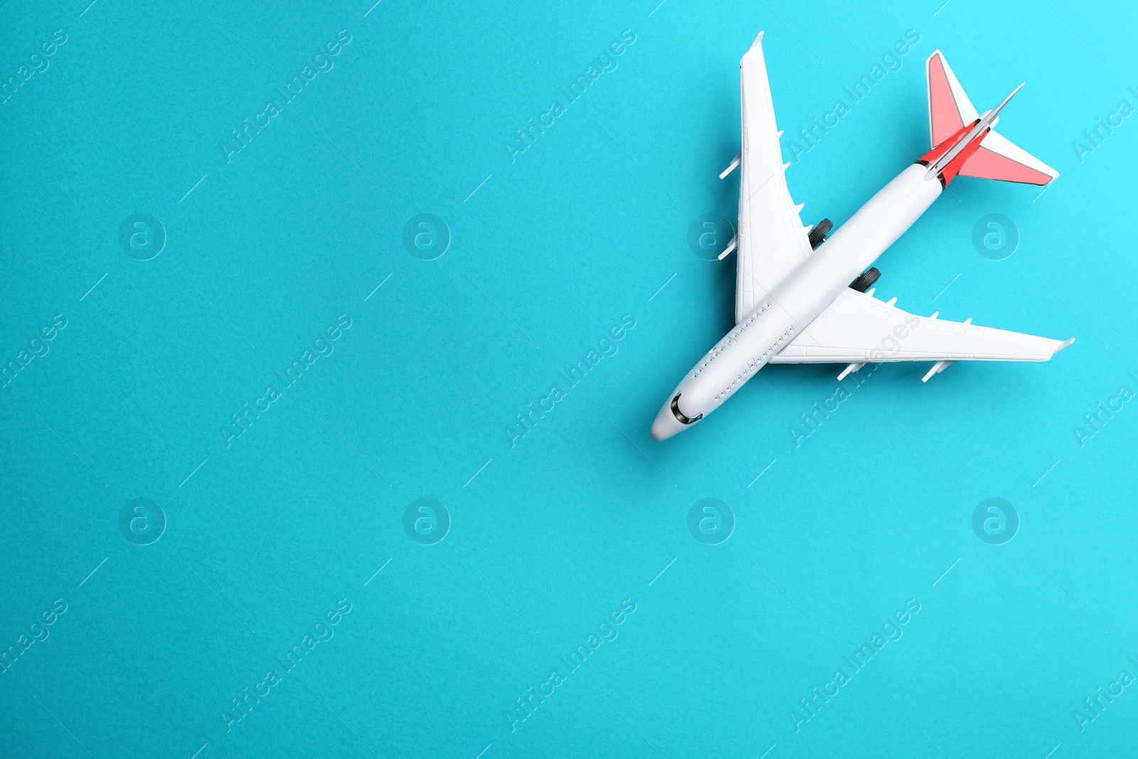 Photo of Toy airplane on light blue background, top view. Space for text