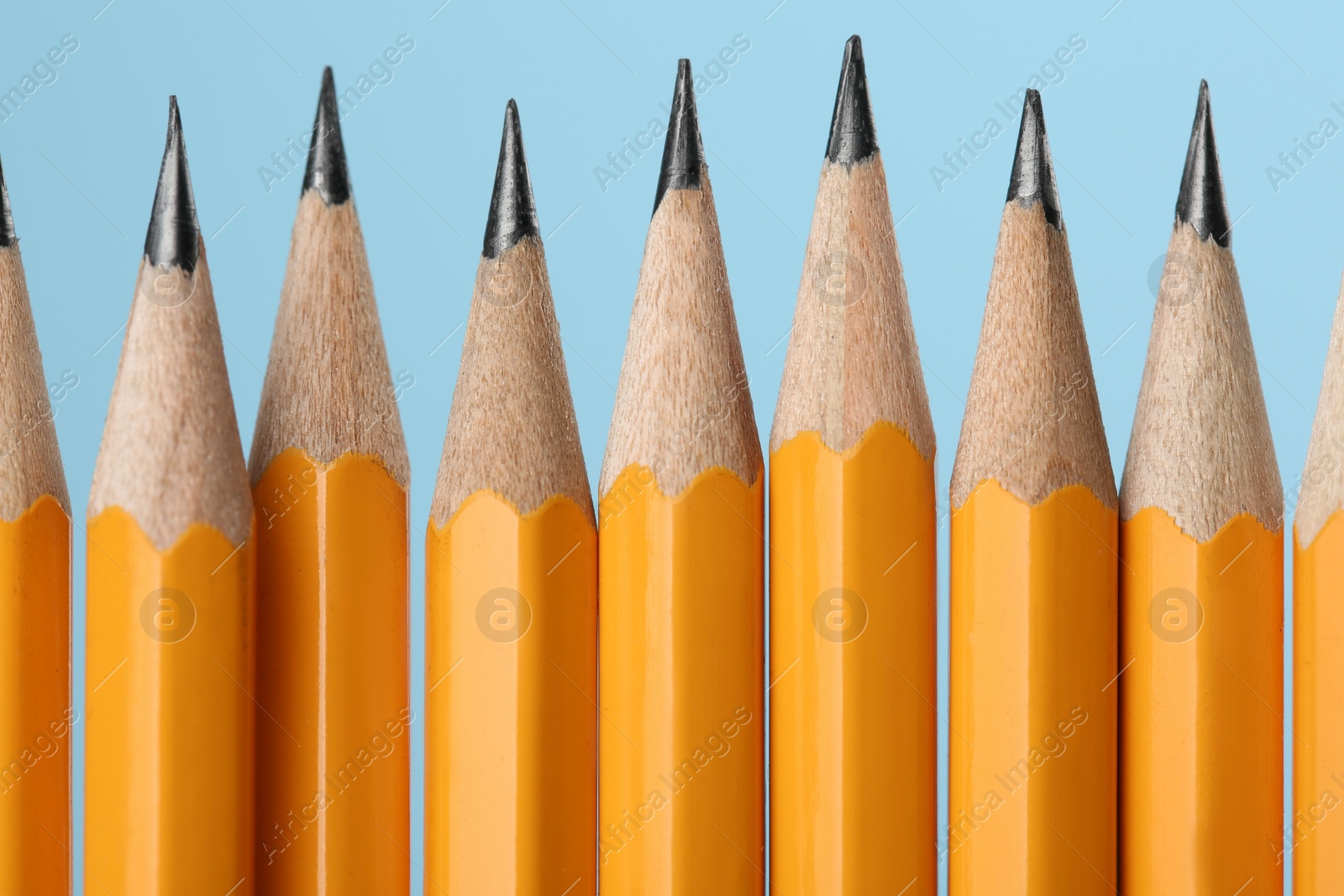 Photo of Many sharp graphite pencils on turquoise background, macro view