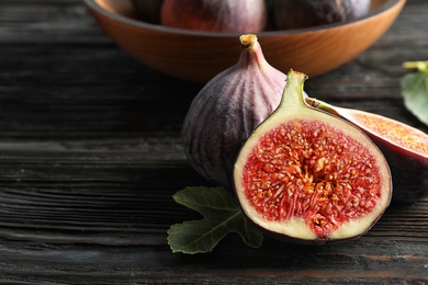 Photo of Fresh ripe figs with leaves on wooden table. Tropical fruit